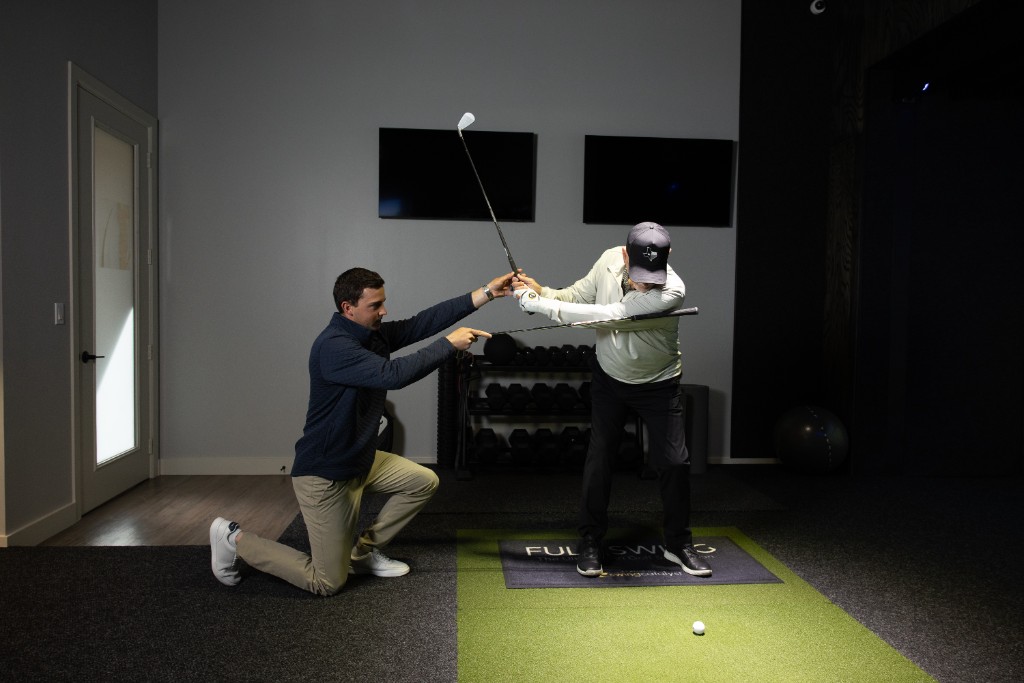 Instructor coaching backswing position in simulator bay